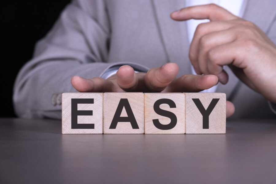 EASY, the word is written on wooden cubes, blocks on the background of a man, a businessman in a gray suit.
